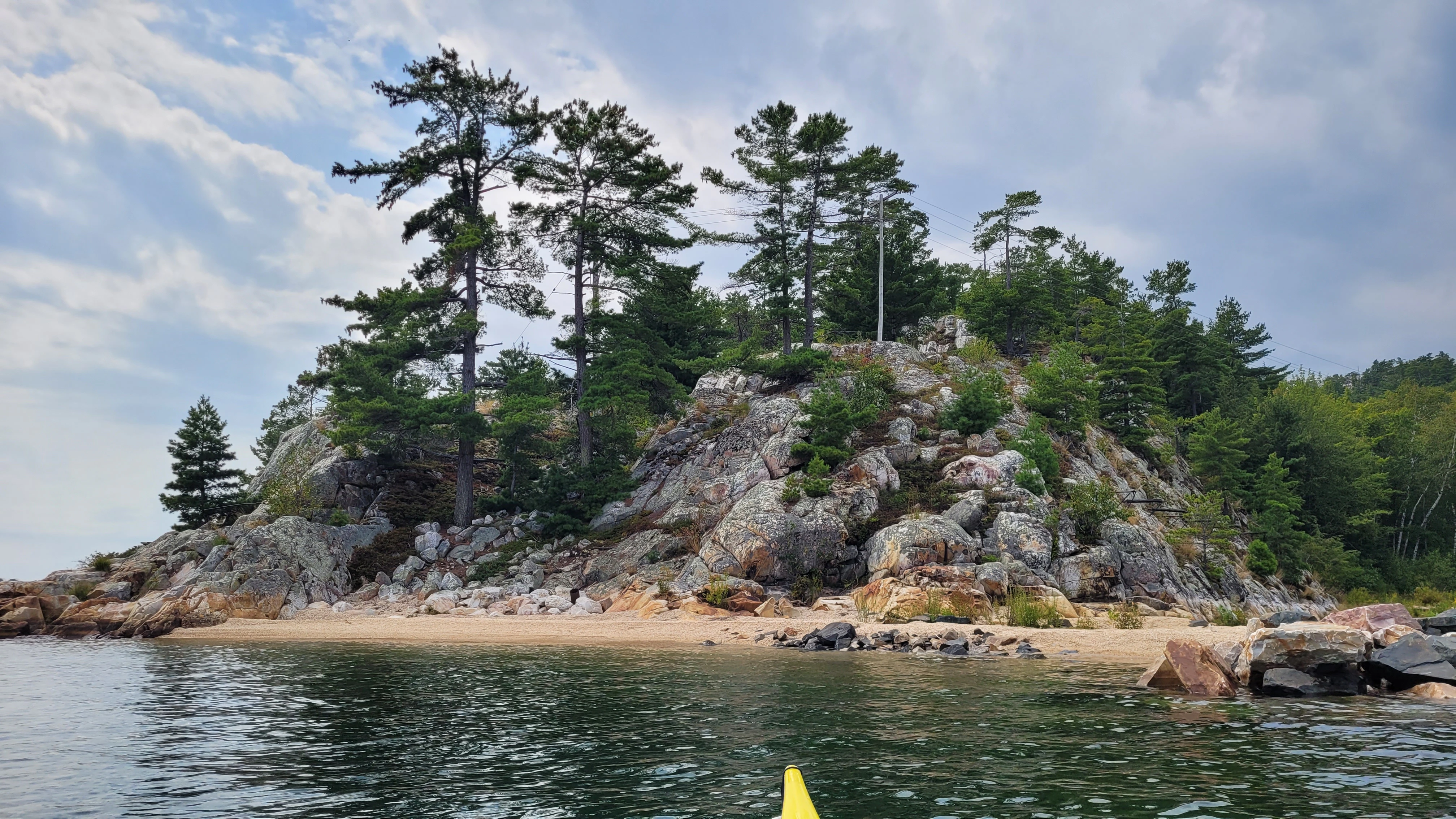 White quartzite cliffs, pine trees and quartzite pebble beach in Killarney Bay Ontario Canada